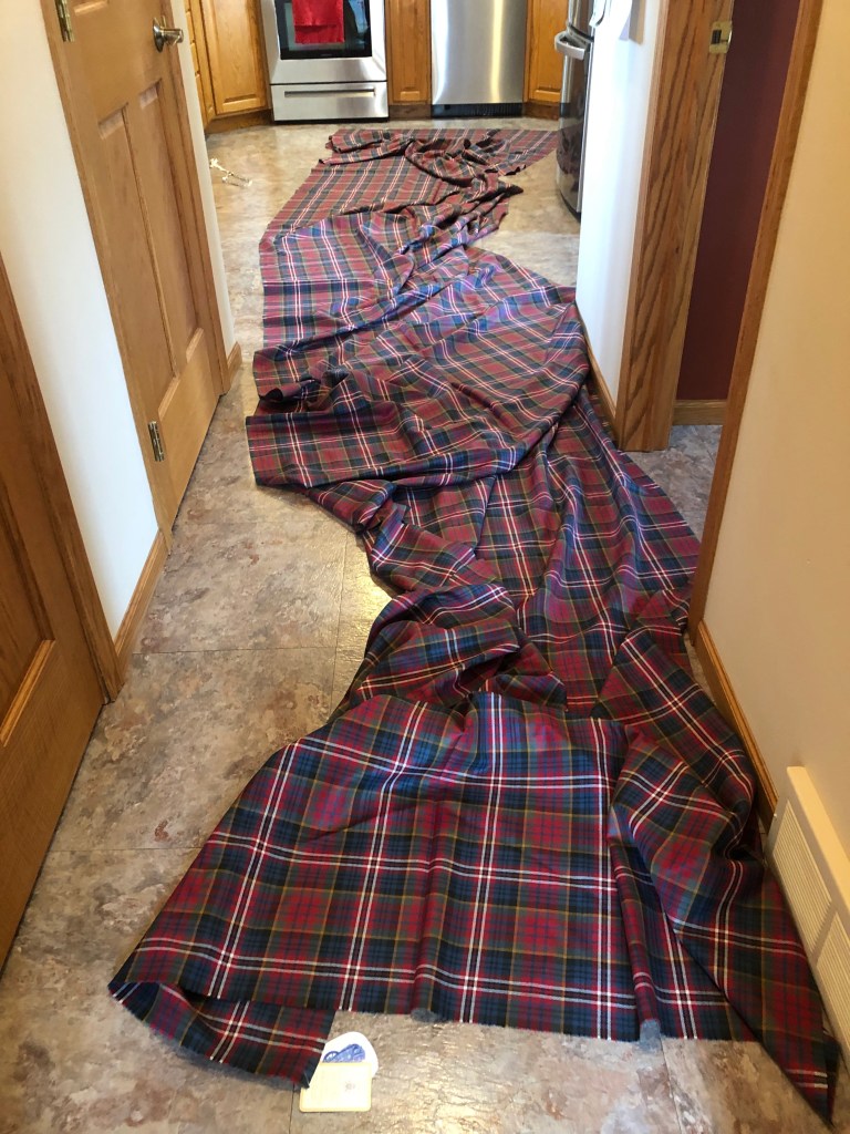 Eight yards of MacPherson Red tartan fabric spread across a kitchen floor