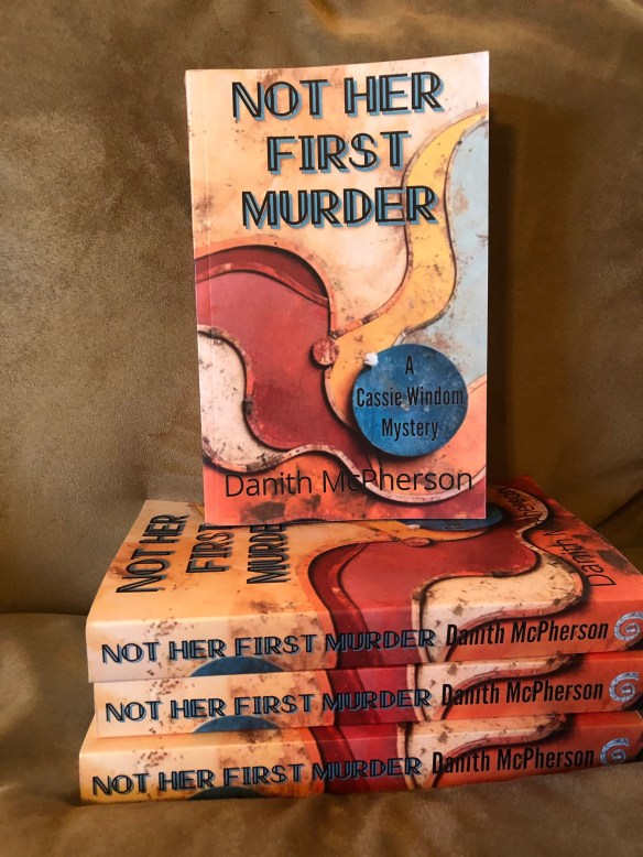 Stack of books titled Not Her First Murder by Danith McPherson
